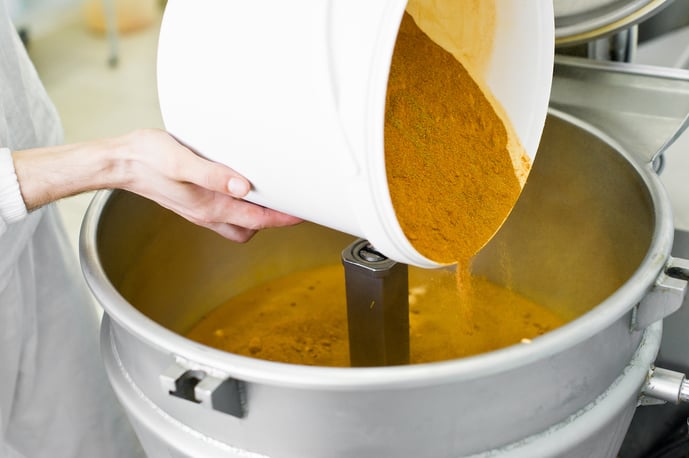 Food powder being poured into an industrial mixer. 