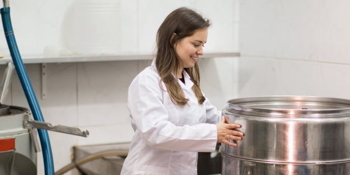 scientist_supports_metal_barrel_in_toll_processing_facility